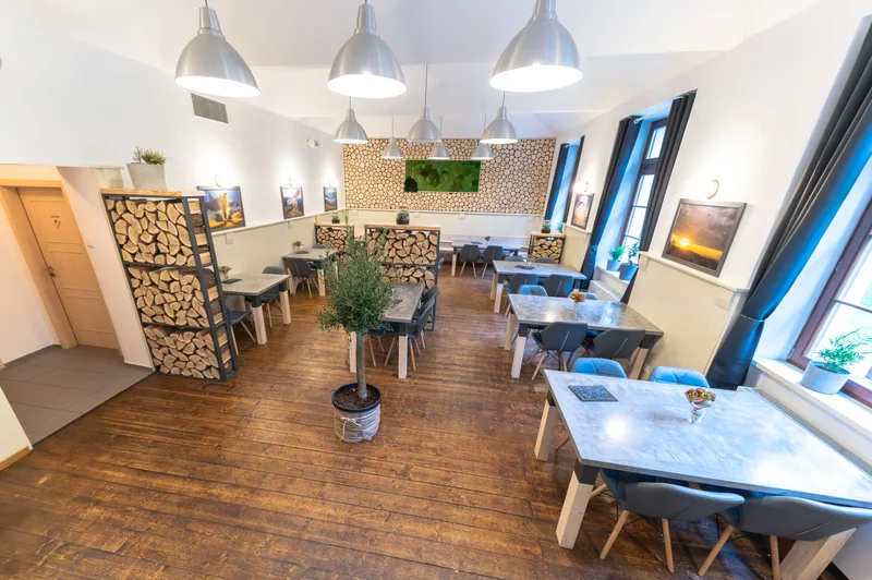 Celkový pohled na restauraci Do Nebe Písek s olivovníkem a naskládanými poleny
